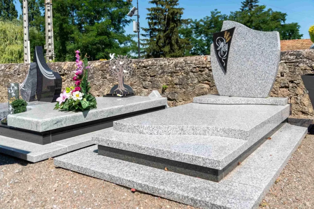 Monuments funéraires en granit gris installés dans un jardin du souvenir.
